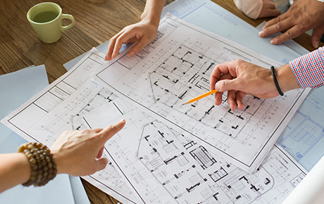team collaborating on architectural blueprints with coffee cup and design plans showcasing layout details for two-story building