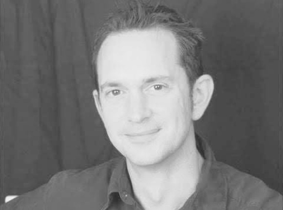 portrait of a man smiling against a dark background showcasing three key qualities of confidence expertise and approachability